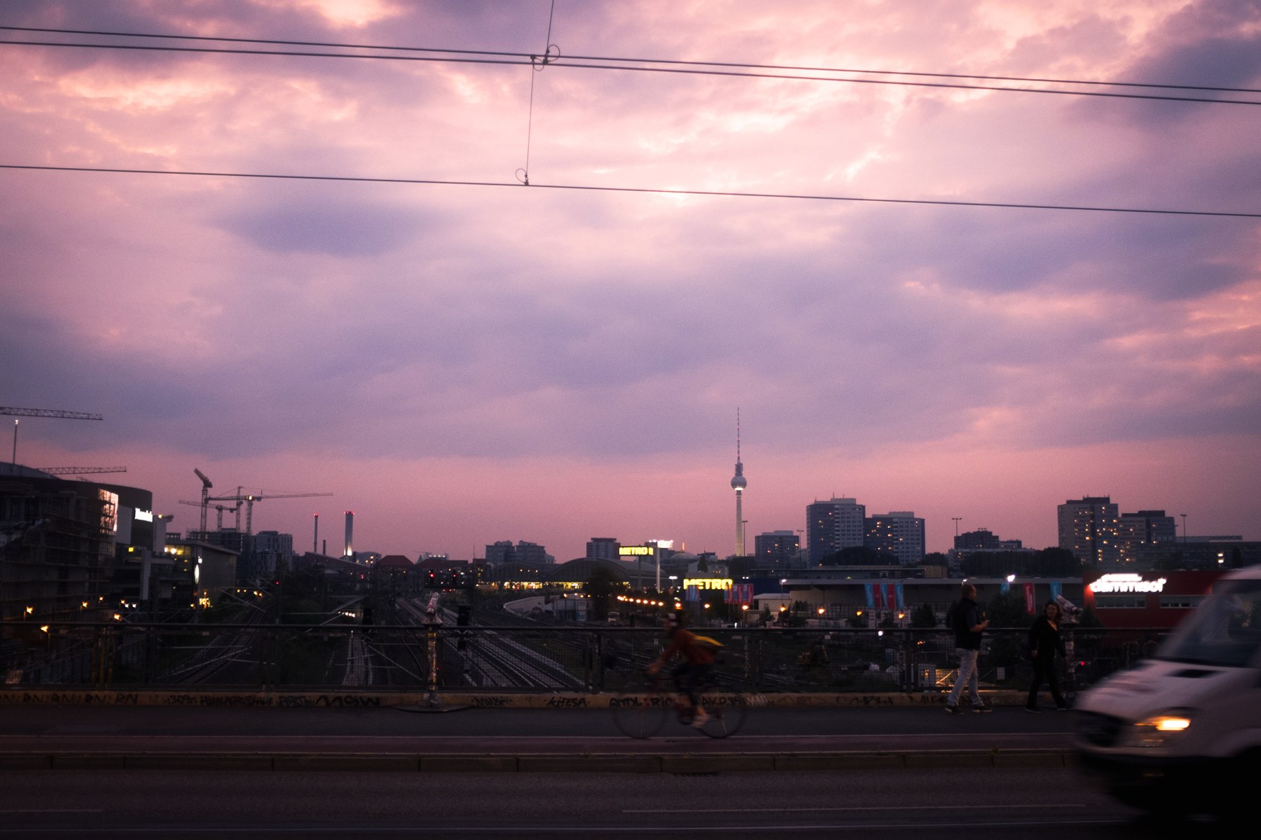 The Berlin sunset graded with peach light, lilac shadows and soft bloom; the wires are still present