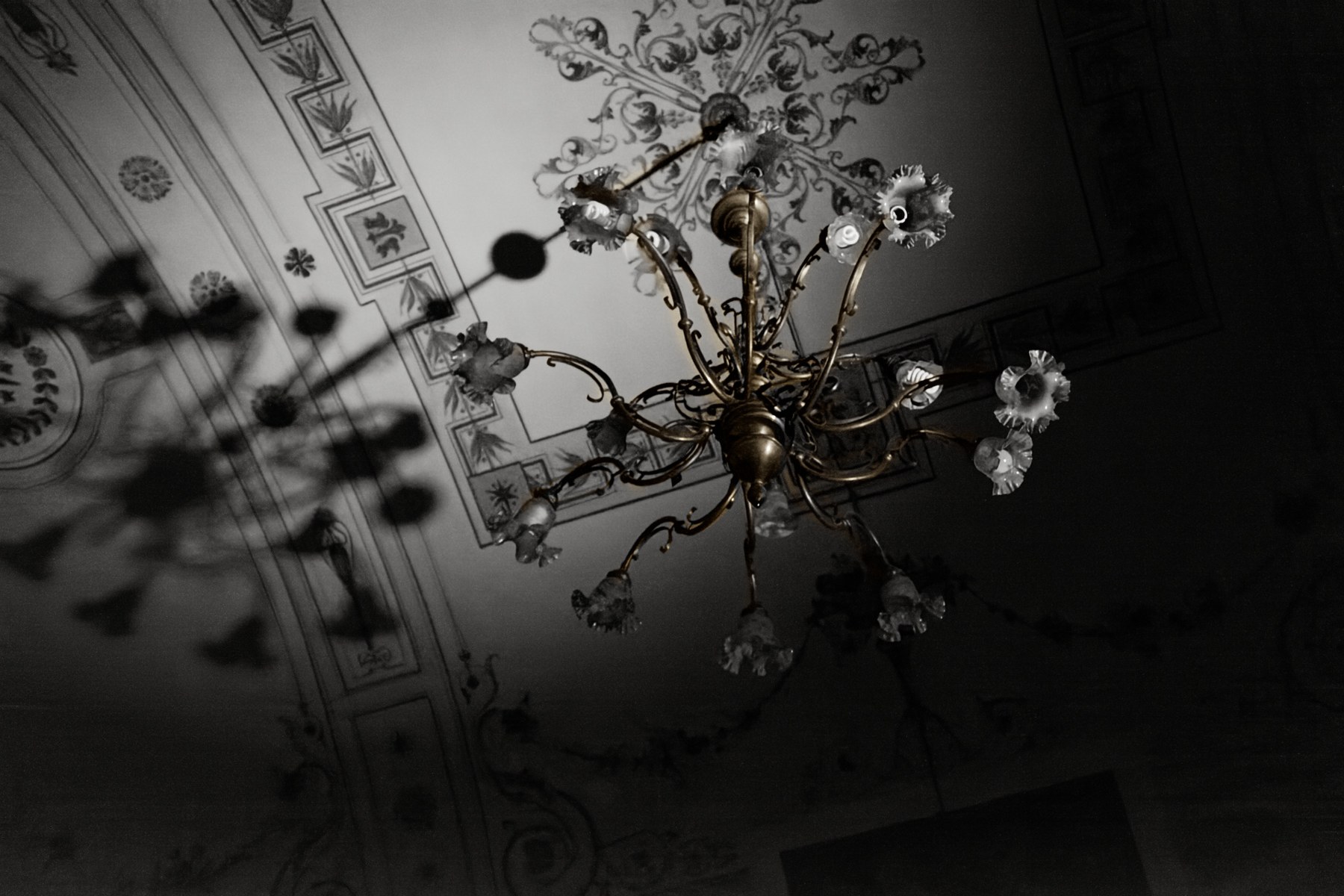 The restored chandelier with warm brass, clearer glass and a neutral ceiling