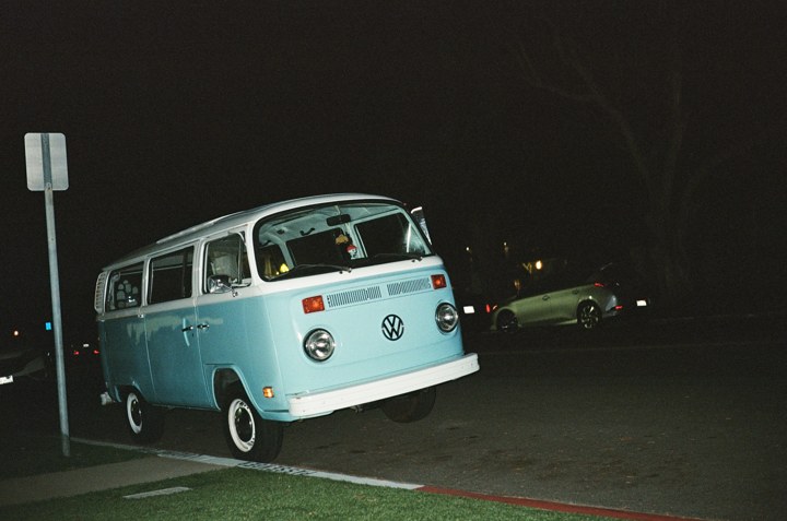 A pale blue Volkswagen van photographed at night
