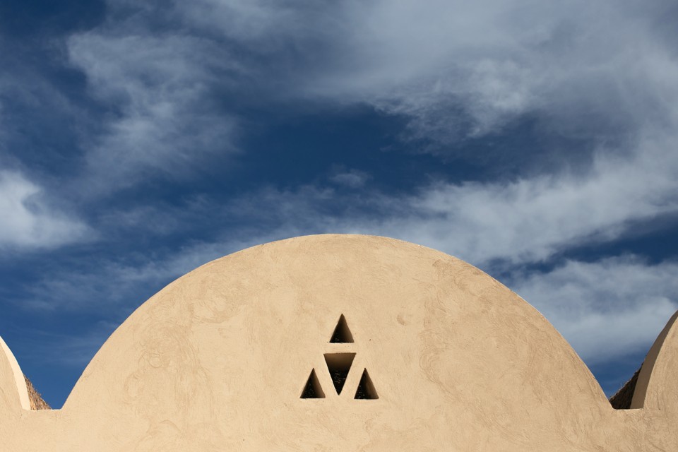 Rounded sand-colored Egyptian architecture against a deep blue cloudy sky